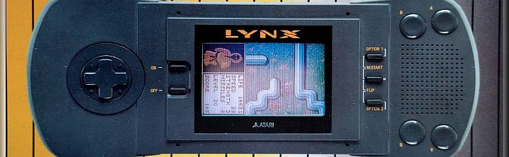 Atari Lynx handheld gaming console with a color game on screen, a left D‑pad, and right-side buttons on a dark body.